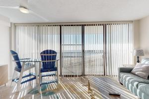 a living room with a glass table and blue chairs at Sea Colony - 702 Dover House Rd. in Bethany Beach