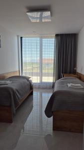 a bedroom with two beds and a large window at Apartman Bartimej 3A in Bobrów