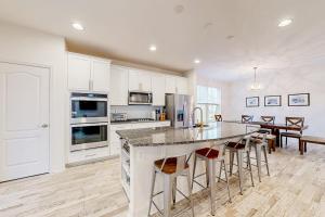 a kitchen with white cabinets and a island with bar stools at The Estuary - 26643 Weathervane Way in Frankford +47 photos
