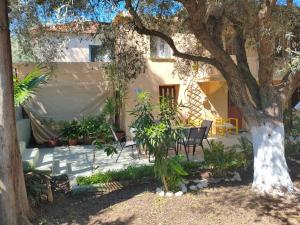 a house with a table and chairs under a tree at Petrohori before midnight in Pylos