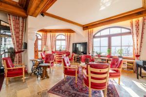 a living room with red chairs and a tv at Hotel Glocknerhof in Berg im Drautal