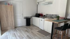 a kitchen with white cabinets and a wooden floor at Studio nature in Saran