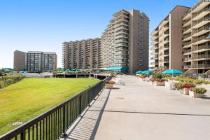 a walkway with tables and umbrellas and some buildings at Sea Colony - 902 Georgetowne House in Bethany Beach