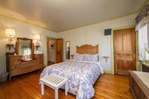 a bedroom with a bed and a dresser and a mirror at Auberge la Romance in La Malbaie
