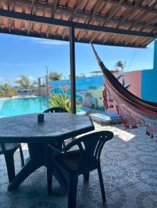 a table and chairs on a patio with a hammock at Pousada Azul da Broadway in Canoa Quebrada