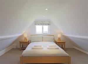 a white bedroom with a bed with two nightstands and a window at 5 Bed in Beccles oc-ksf in Wangford