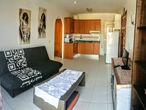 a living room with a black couch and a kitchen at Monseñor in Playa del Cura