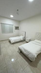 a room with two beds and a chalkboard on the wall at شقق ابو طلال المفروشة in Sakakah