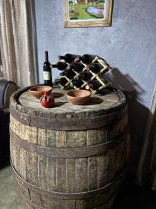 ein Holzfass mit zwei Schüsseln und Flaschen Wein in der Unterkunft Sameba House in Khuts'ubani