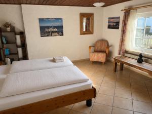 a bedroom with two beds and a chair and a window at Reetdachtraum in Middelhagen
