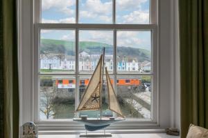 a toy boat sitting in a window with a view at Angorfa Aberaeron Apartment in Aberaeron