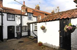 a row of white houses with potted plants on them at 1 Bed in Southwold oc-aapebb in Southwold