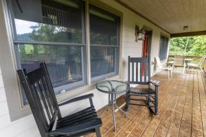 a porch with two chairs and a glass table at Mountain Melody in Blowing Rock