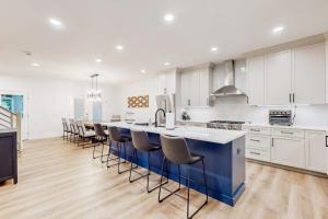 a kitchen with white cabinets and a blue island with bar stools at The Peninsula --- 33129 Serenity Circle #87 in Millsboro +42 photos