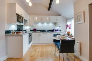 a kitchen with white cabinets and a table with chairs at Becws Clyd in Trawsfynydd