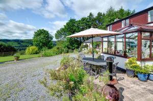 a patio with an umbrella and a table and chairs at 3 Bed in Llanidloes oc-waa246 in Llangurig