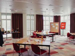 a conference room with tables and chairs and windows at ibis Hotel Regensburg City in Regensburg