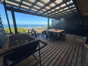 a wooden deck with a table and chairs and the ocean at Almar House in Guaquen