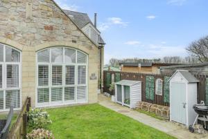 a stone house with a garden and a fence at Smugglers Hide in Beadnell