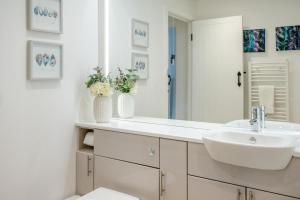 a white bathroom with a sink and a mirror at Smugglers Hide in Beadnell +37 photos
