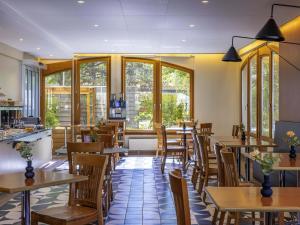 a restaurant with tables and chairs and windows at Ibis Sion in Sion