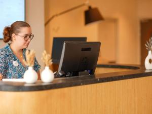 a woman sitting at a counter with a laptop computer at Mercure Colmar Centre Unterlinden in Colmar