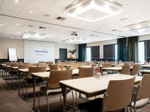 a large room with tables and chairs and a presentation at Novotel Atria Nimes Centre in Nîmes