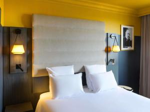 a bedroom with a bed with white pillows and two lights at Mercure Honfleur in Honfleur +28 photos