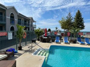 a swimming pool with blue chairs and a building at Lakeview Resort Motel in Wasaga Beach