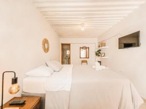 a white bedroom with a bed and a table at La Jaus by Hope in Guatapé