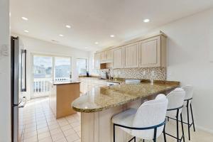 a kitchen with white cabinets and a island with bar stools at South Bethany --- 309 W 2nd St in Bethany Beach +18 photos