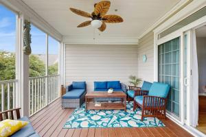 a porch with blue chairs and a table and a fan at Bear Trap Dunes --- 124 October Glory Ave Unit #B in Ocean View
