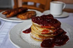 a stack of pancakes with jam on a white plate at Saxonis Houses & Saxonis Villa in Papigko +52 photos