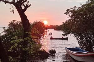 a boat on a river with the sunset in the background at Poneloya Budget Accomodations in León