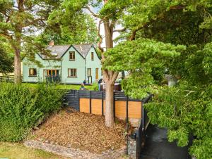 a house with a tree in front of a fence at Mountain View Cottage, Hot Tub , Stunning Views in Llanhamlach