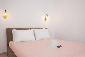 a bed with white pillows and a hat on it at Paradissi Marmara in Cherronisos