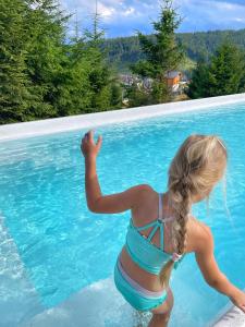a little girl in a bikini standing in a swimming pool at be be Chalet mini - privat pool & jacuzi in Bukovel