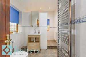 a bathroom with a sink and a mirror at Mountain View Cottage, Hot Tub , Stunning Views in Llanhamlach