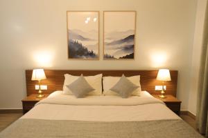 a bedroom with a large bed with two lamps at Two Seas Residence - Boutique Residences in Ooty