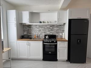 a kitchen with white cabinets and a black refrigerator at Modern Tropical Oasis in Sosúa