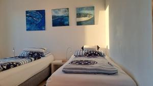 two beds in a room with paintings on the wall at Meerferienwohnungen Kühlungsborn in Kühlungsborn