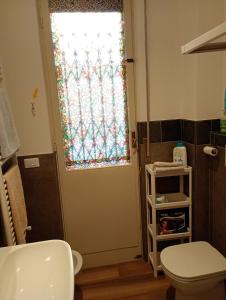 ein Badezimmer mit Toilette und einer Tür mit Fenster in der Unterkunft Cozy!! Verona in Verona