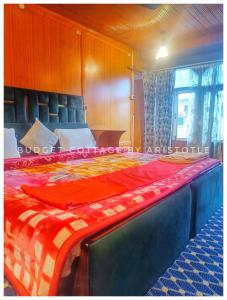 a bedroom with a bed with a red blanket on it at Budget Cottage By Aristotle in Srinagar