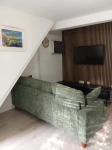a living room with a green couch and a television at Swannery Vista 1 Bedroom Apartment in Weymouth
