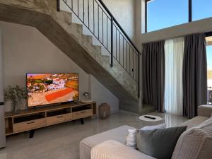 a living room with a tv and a staircase at ZOSANA Villa in Kallithea Halkidikis