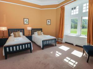 a bedroom with two beds and a large window at Bynack - Mar Lodge Estate in Ballater