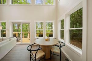 a dining room with a table and chairs and windows at Appalachian Cottage in Blowing Rock
