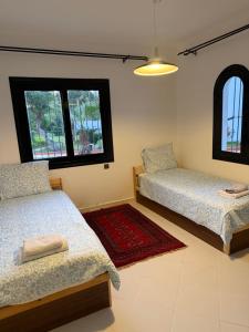 two beds in a room with two windows at Soumaya plage appartement in Fnidek