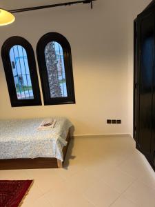 a bedroom with three windows and a bed at Soumaya plage appartement in Fnidek