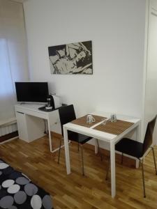 Habitación con escritorio, mesa blanca y sillas. en B&B Stazione Latina en Sermoneta